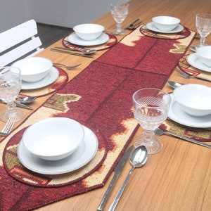 Pode incluir: Uma mesa de jantar montada para uma refeição, com tigelas, pratos e copos brancos. A mesa é adornada com um corredor de mesa com padrão vermelho e bege e jogos americanos a condizer. A prataria está cuidadosamente disposta.