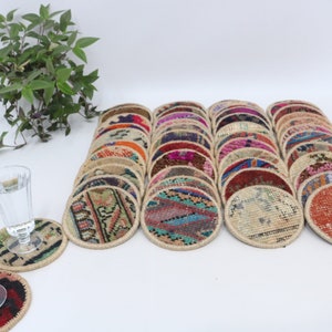 May include: A set of 25 colorful round coasters made from repurposed rug scraps. Each coaster features a unique pattern and color combination. The coasters are perfect for adding a touch of bohemian style to your home.