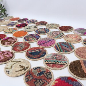 May include: A collection of round, colorful, woven coasters with intricate patterns. The coasters are made of fabric and have a natural fiber trim.