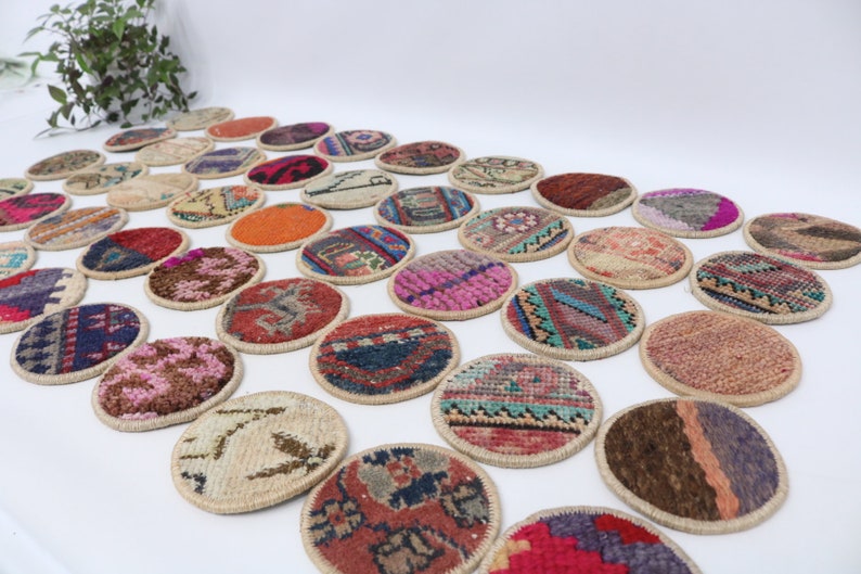 May include: A collection of round, colorful, woven coasters with intricate patterns. The coasters are made of fabric and have a natural fiber trim.