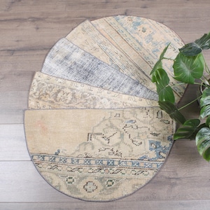 May include: A circular, patchwork rug with a variety of faded colors, including beige, blue, and gray. The rug is composed of several pie-shaped sections, each with a unique pattern. A potted plant with large green leaves sits nearby.