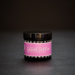 May include: A black jar with a pink label that reads "100% Natural Ingredients. Always. Ladies Love It. Moisturize. Shine. Grow."