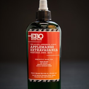 May include: A green bottle of EBO beard wash with a red and orange label. The label reads "100% Natural Ingredients. Always. Applemango Extravaganza. Moisturize. Shine. Grow." and "Perfectly Made For Thick Beards, Dry Beards, Growth Stimulation and All Grooming Needs."