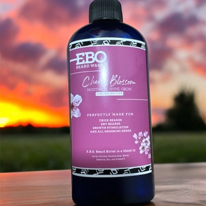 May include: A blue bottle of EBO Beard Wash in Cherry Blossom scent. The bottle has a black cap and a label with white text that reads "EBO Beard Wash Cherry Blossom Moisturize. Shine. Grow! Limited Edition Perfectly Made For Thick Beards Dry Beards Growth Stimulation And All Grooming Needs E.B.O. Beard Butter is a blend of: An All Natural Shampoo Base, Water, Essential Oils, and Vitamin E."
