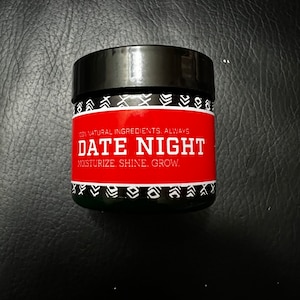 May include: A red and black jar with the text "100% NATURAL INGREDIENTS. ALWAYS. DATE NIGHT. MOISTURIZE. SHINE. GROW." on the label.