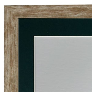 May include: A wood picture frame with a dark green mount. The frame has a light brown wood finish.