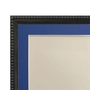 May include: A black picture frame with a blue mat. The frame has a beaded edge.