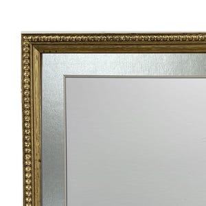 May include: A gold picture frame with a silver mount. The frame has a beaded design around the edge.