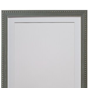 Peut inclure: Un cadre photo rectangulaire avec une finition gris-vert et un passe-partout blanc. Le cadre a un bord perlé et un design simple et élégant. Le cadre est vide, prêt à afficher une photo ou une œuvre d'art.
