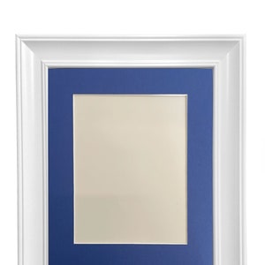 May include: White picture frame with a blue mat. The frame has a simple, classic design.