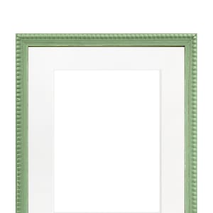 Peut inclure: Un cadre photo vert avec un passe-partout blanc. Le cadre a un motif de perles autour du bord.