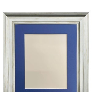 May include: A silver picture frame with a blue mount. The frame has a distressed wood-like finish.