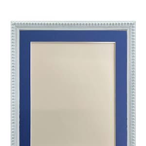 Peut inclure: Un cadre photo rectangulaire avec une bordure perlée blanche et un passe-partout bleu. Le cadre a un intérieur beige clair et est conçu pour contenir une photo ou une œuvre d'art. Le cadre est un objet décoratif.