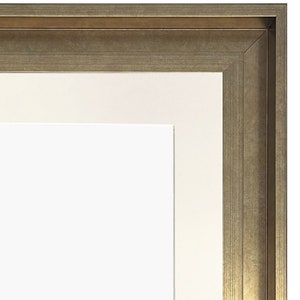 May include: A close-up of the top corner of a picture frame with a gold-toned wood frame and a white mat.