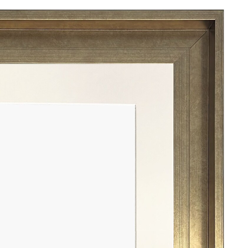 May include: A close-up of the top corner of a picture frame with a gold-toned wood frame and a white mat.