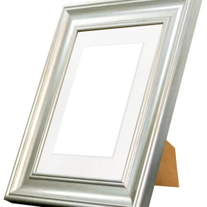 May include: A silver picture frame with a white mat and a wooden easel stand.
