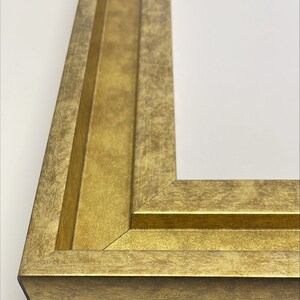 May include: Close-up of a corner of a gold picture frame with a distressed finish. The frame has a double-layered molding.