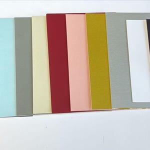 May include: A collection of 10 different coloured cardstock paper sheets. The colours are black, dark blue, light blue, grey, beige, cream, red, pink, gold, and silver.