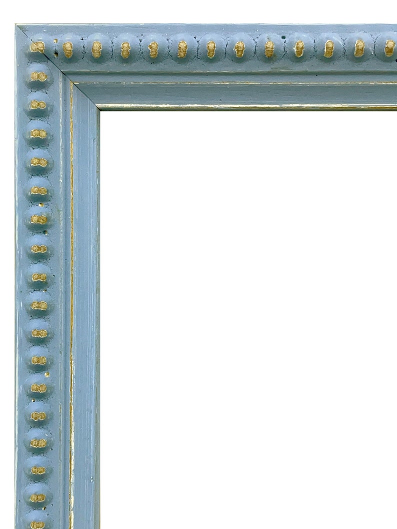 Pu&ograve; includere: Una cornice per foto blu chiaro con un bordo dorato. La cornice ha un bordo perlato decorativo.