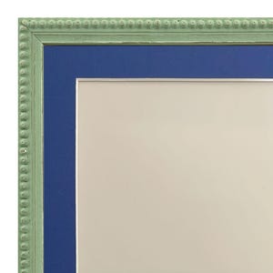 Puede incluir: Un marco de imagen verde con un passe-partout azul y un fondo blanco. El marco tiene un borde de cuentas.