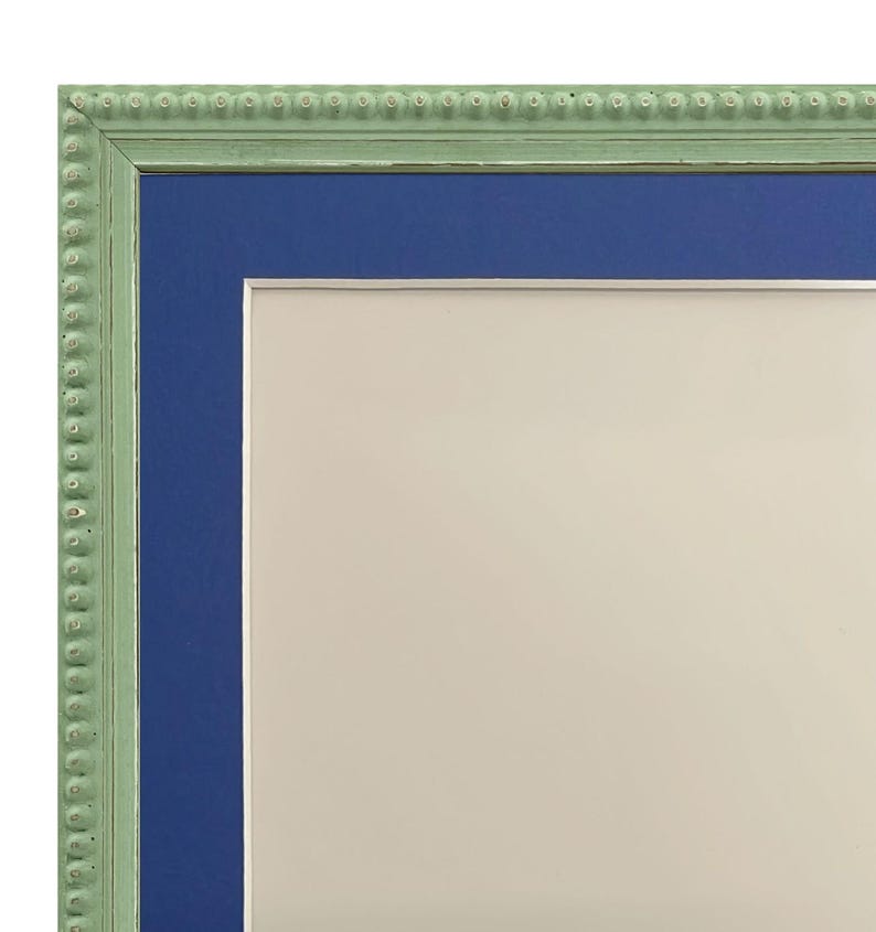 Puede incluir: Un marco de imagen verde con un passe-partout azul y un fondo blanco. El marco tiene un borde de cuentas.