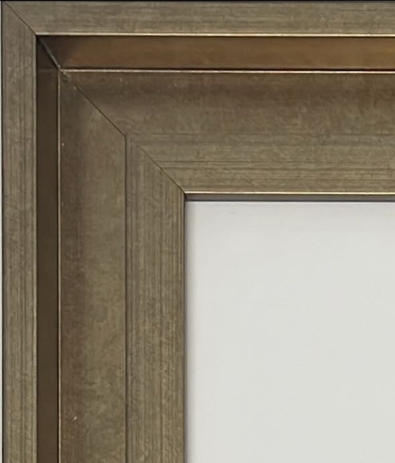 K&ouml;nnte beinhalten: Nahaufnahme eines Bilderrahmens aus Holz mit goldfarbener Oberfl&auml;che. Der Rahmen hat ein schlichtes, klassisches Design mit einem leicht erh&ouml;hten Rand.
