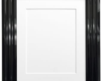 May include: A rectangular picture frame with a glossy black finish and a stepped, multi-layered profile. The frame features a wide, smooth border surrounding a clean, white rectangular mat board that creates a centered opening for display.
