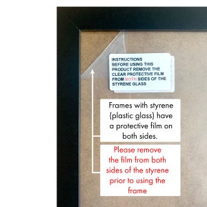 May include: Close-up of a black picture frame with a brown mount. The frame has a protective film on both sides. The text on the film reads: "INSTRUCTIONS BEFORE USING THIS PRODUCT REMOVE THE CLEAR PROTECTIVE FILM FROM BOTH SIDES OF THE STYRENE GLASS. Frames with styrene (plastic glass) have a protective film on both sides. Please remove the film from both sides of the styrene prior to using the frame."