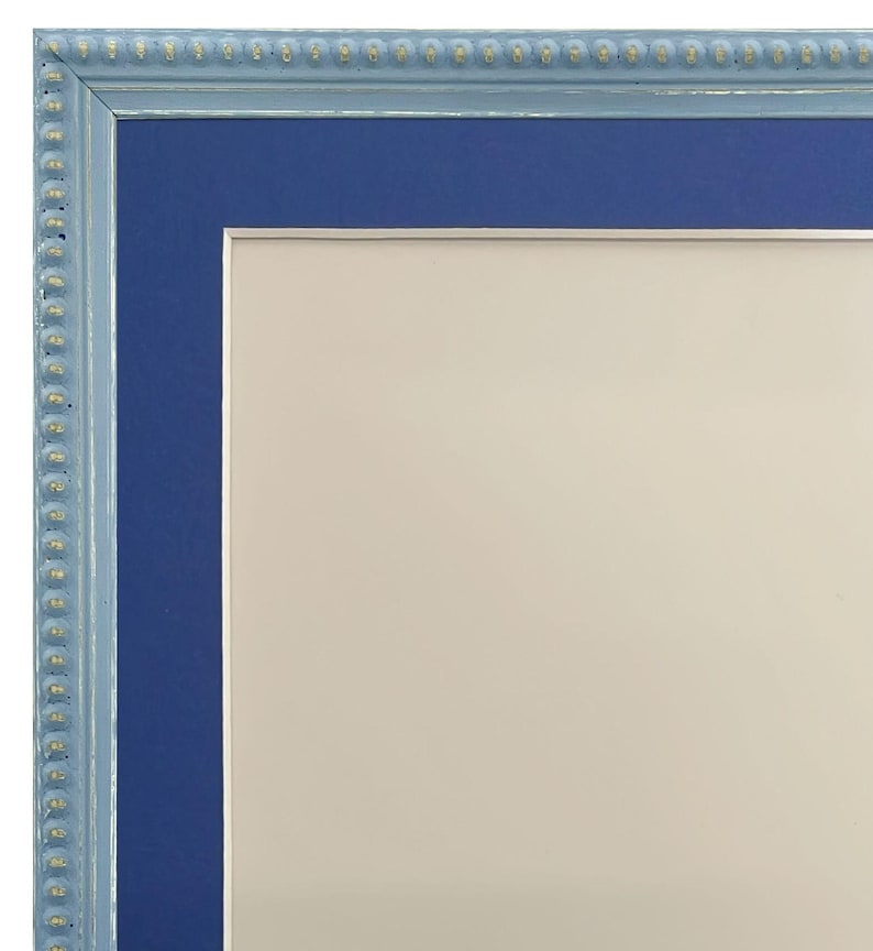 Pu&ograve; includere: Una cornice per foto blu con una cornice esterna blu chiaro e un bordo di perline dorate. La cornice &egrave; vuota.