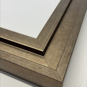 May include: Close-up of the corner of a double-layered picture frame with a brushed gold finish.