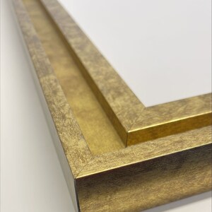 K&ouml;nnte beinhalten: Nahaufnahme eines goldenen Bilderrahmens mit doppelter Passepartout. Der Rahmen hat eine abgenutzte Oberfl&auml;che und einen leicht erh&ouml;hten Rand.