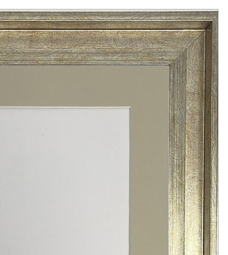 May include: A silver picture frame with a wide, ornate border and a beige mat. The frame has a distressed, antique look.
