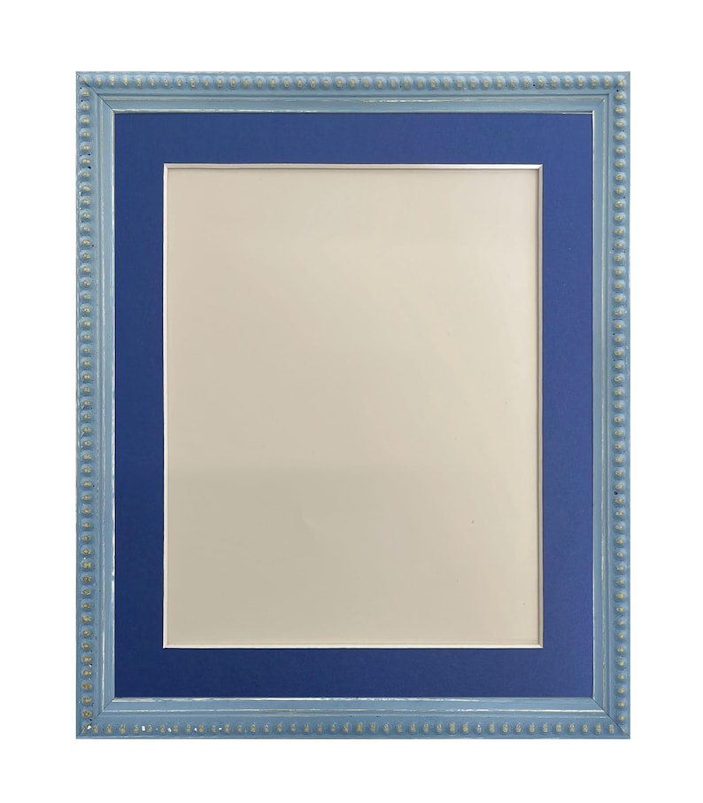 Pu&ograve; includere: Una cornice per foto blu chiaro con un passepartout blu scuro. La cornice ha un bordo perlato.