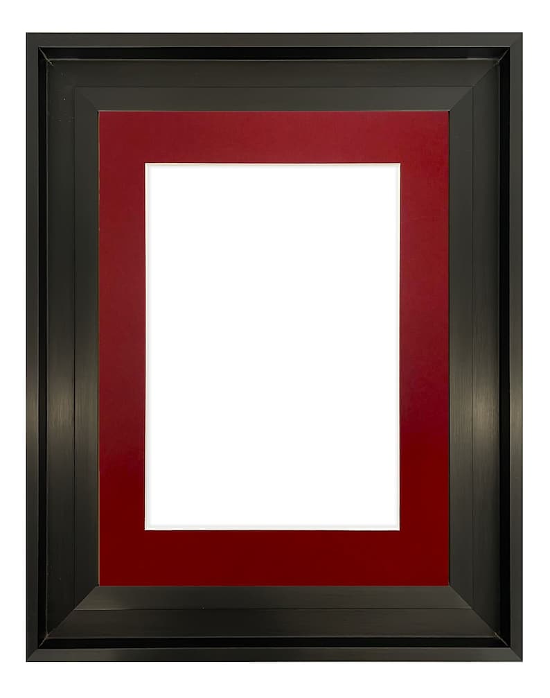 K&ouml;nnte beinhalten: Ein rechteckiger Bilderrahmen mit einem schwarzen Au&szlig;enrahmen und einem tiefroten Innenpassepartout. Der Rahmen hat eine wei&szlig;e &Ouml;ffnung in der Mitte, die f&uuml;r ein Foto oder Kunstwerk vorgesehen ist. Der Rahmen ist aus Holz.