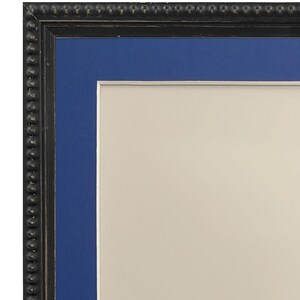 May include: A black picture frame with a blue mat and a white background. The frame has a decorative beaded edge.