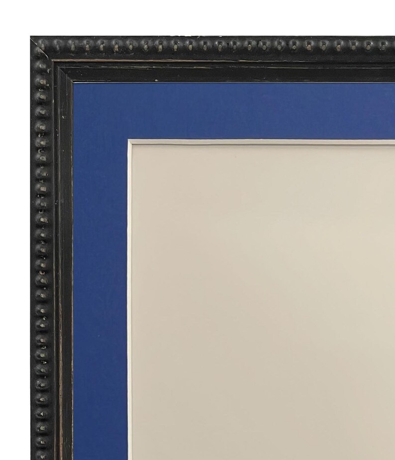 May include: A black picture frame with a blue mat and a white background. The frame has a decorative beaded edge.