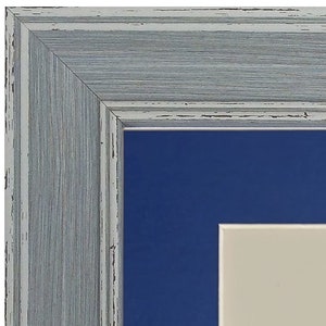 Peut inclure: Gros plan sur un cadre photo en bois gris avec un passe-partout bleu et un passe-partout int&eacute;rieur blanc. Le cadre a un aspect vieilli.