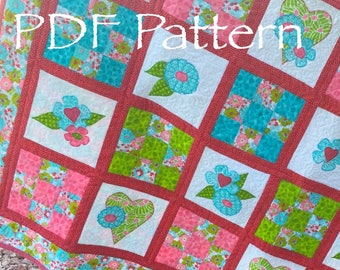 Könnte beinhalten: Ein PDF-Muster für eine Steppdecke mit einem Patchwork-Design mit Herzen, Blumen und Quadraten in den Farben Rosa, Grün, Blau und Weiß. Die Steppdecke ist aus verschiedenen Stoffen gefertigt und hat einen roten Rand.