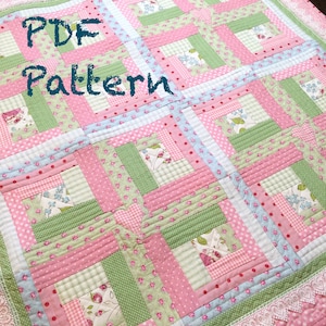 May include: A PDF pattern for a quilt with a log cabin design. The quilt is made with pink, green, and blue fabrics with floral and polka dot patterns. The quilt is edged with white lace.