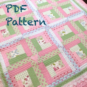 May include: A PDF pattern for a quilt with a log cabin design. The quilt is made with pink, green, and blue fabrics with floral and polka dot patterns. The quilt is edged with white lace.