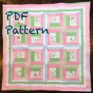 May include: A PDF pattern for a quilt with a log cabin design. The quilt is made with pink, green, and blue fabrics with floral and polka dot patterns. The quilt is surrounded by a white lace border.