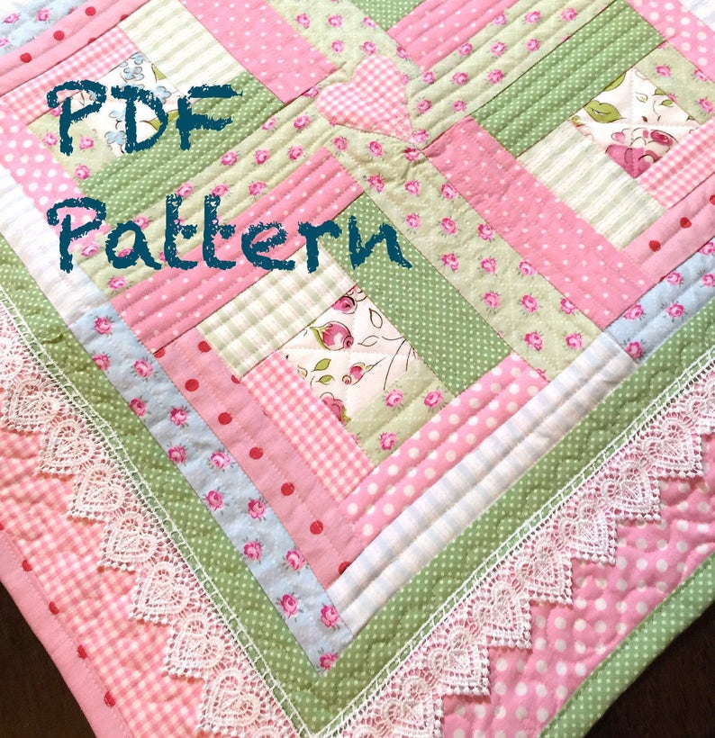 May include: A PDF pattern for a quilt with a pink and green color scheme. The quilt is made of various fabrics with floral, polka dot, and plaid patterns. The quilt is edged with white lace.