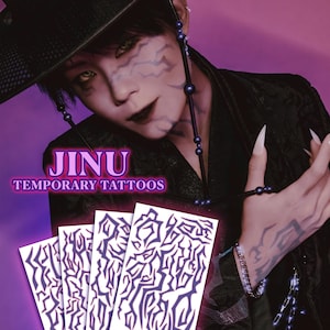 May include: Image of temporary tattoos with a dark purple design. The image includes the text "JINU TEMPORARY TATTOOS". The tattoos are displayed on white cards. The background is a gradient of purple and pink.