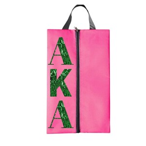 K&ouml;nnte beinhalten: Rosa Schuhbeutel mit Rei&szlig;verschluss und einem gr&uuml;nen Pailletten-Design mit der Aufschrift "AKA".