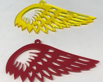 May include: Two decorative acrylic wings, one yellow and one red, with a cut-out design. The wings have a hole at the top for hanging.