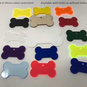 May include: Assortment of bone-shaped acrylic dog tags in various colors, including black, white, red, blue, green, yellow, and purple. Some tags have holes, while others do not.