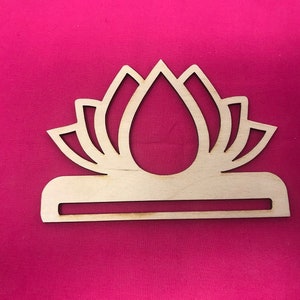 May include: A wooden cutout of a lotus flower with a slot in the base. The cutout is light brown and has a simple design.
