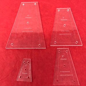 May include: Four clear acrylic templates for making Dresden quilt blocks. The templates are labeled 1", 2", 3", and 4" Dresden. Each template includes a 1/4" seam allowance and the website ANBCOLLECTIBLES.COM.