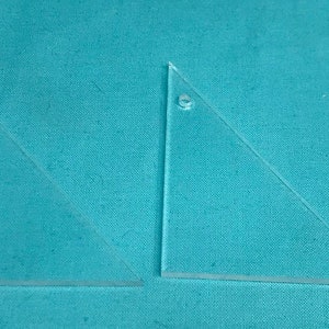 May include: Two clear plastic triangles, one with a small hole in the top corner.