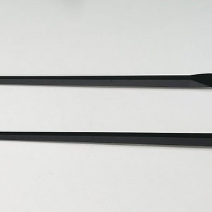 May include: Two black clock hands, one long and one short, for a clock face.